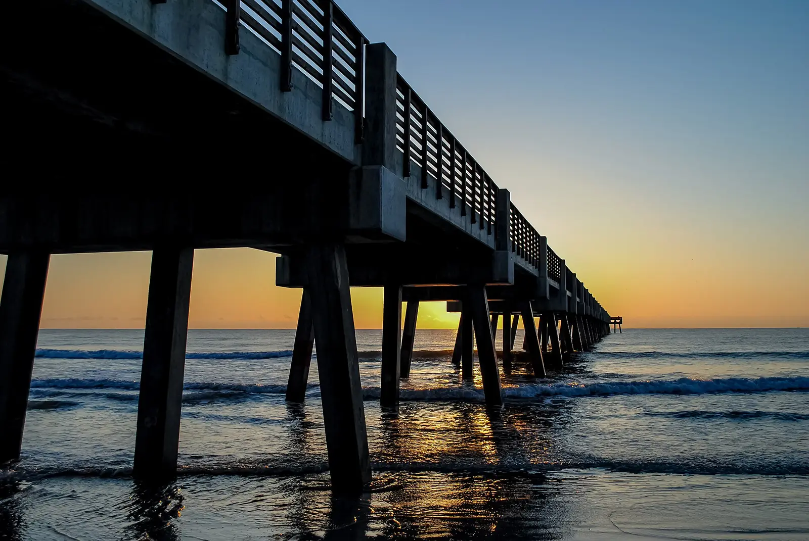Concrete pilings of the Jacksonville Beach pier over the Atlantic Ocean at sunrise
